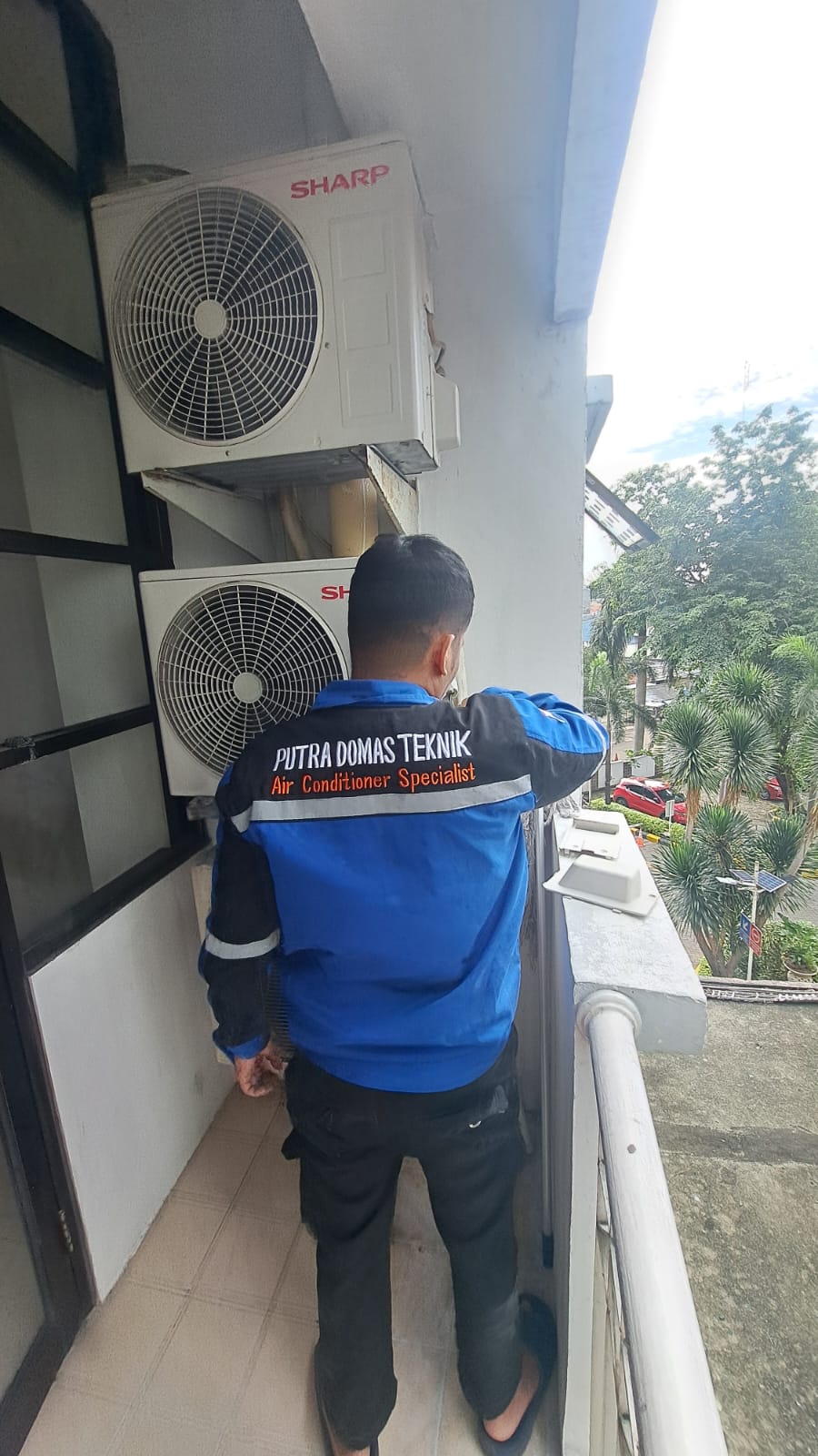Foto outdoor unit AC yang sedang diservice oleh teknisi