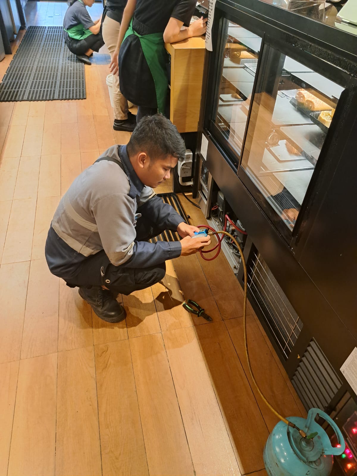 Teknisi melakukan pengisian freon pada unit AC